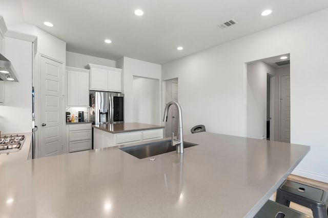 kitchen with visible vents, a kitchen island, recessed lighting, appliances with stainless steel finishes, and a sink