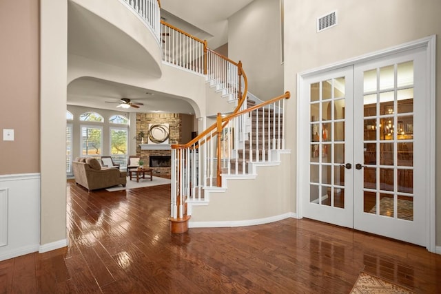 entrance foyer with visible vents, hardwood / wood-style floors, french doors, a fireplace, and a high ceiling