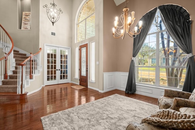 entrance foyer featuring visible vents, stairway, french doors, an inviting chandelier, and wood-type flooring