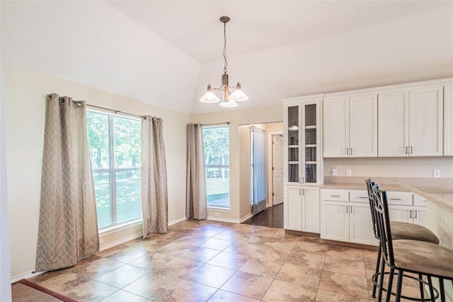 kitchen with white cabinets, light countertops, a chandelier, vaulted ceiling, and pendant lighting