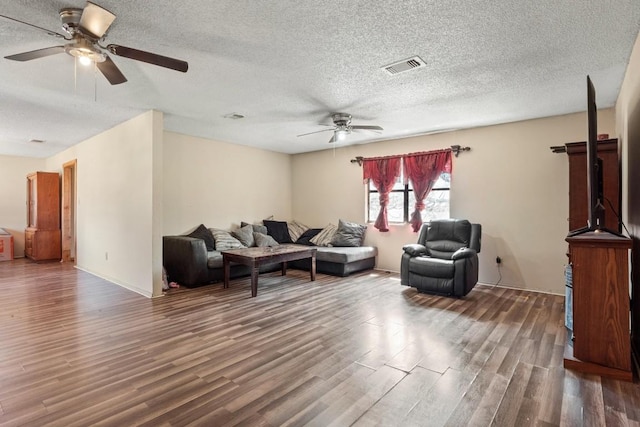 living area with a ceiling fan, wood finished floors, visible vents, and a textured ceiling