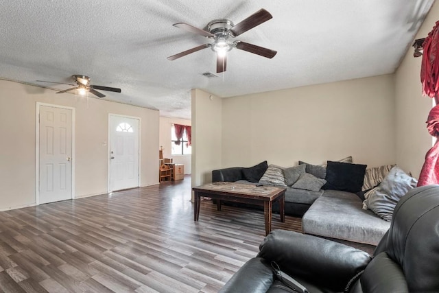 living room with visible vents, a textured ceiling, wood finished floors, and a ceiling fan