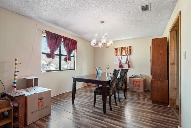 dining space with dark wood finished floors, visible vents, a healthy amount of sunlight, and an inviting chandelier