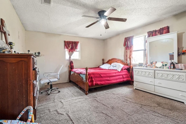 bedroom featuring visible vents, a textured ceiling, a ceiling fan, and carpet floors