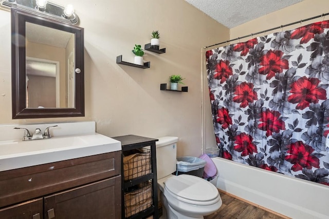 bathroom featuring vanity, wood finished floors, a textured ceiling, toilet, and shower / tub combo with curtain