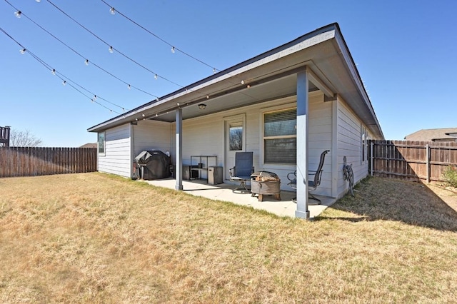 back of house with a fenced backyard, a lawn, an outdoor fire pit, and a patio