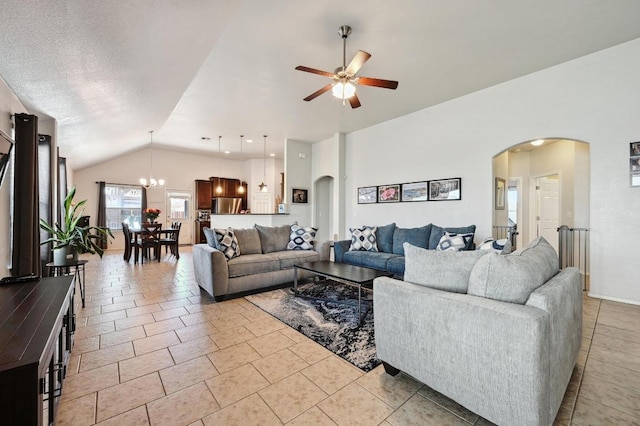 living area with arched walkways, ceiling fan with notable chandelier, and vaulted ceiling