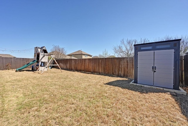 view of yard featuring an outbuilding, a playground, a fenced backyard, and a shed