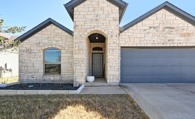 french provincial home featuring a garage, stone siding, and driveway