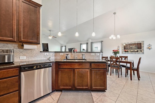 kitchen with dark stone counters, light tile patterned floors, a peninsula, stainless steel appliances, and a sink