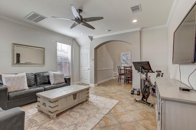 living area with arched walkways, visible vents, ceiling fan, and ornamental molding