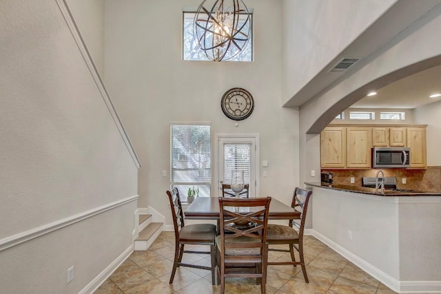 dining room with visible vents, baseboards, recessed lighting, a high ceiling, and arched walkways