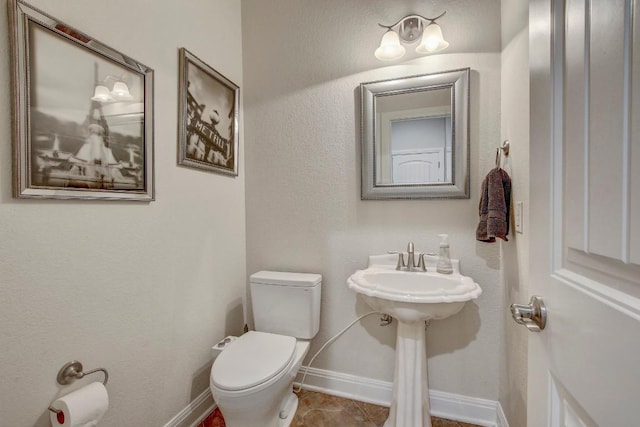 half bath with tile patterned floors, toilet, and baseboards