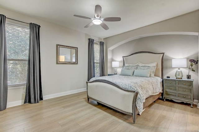 bedroom with multiple windows, a ceiling fan, baseboards, and light wood finished floors