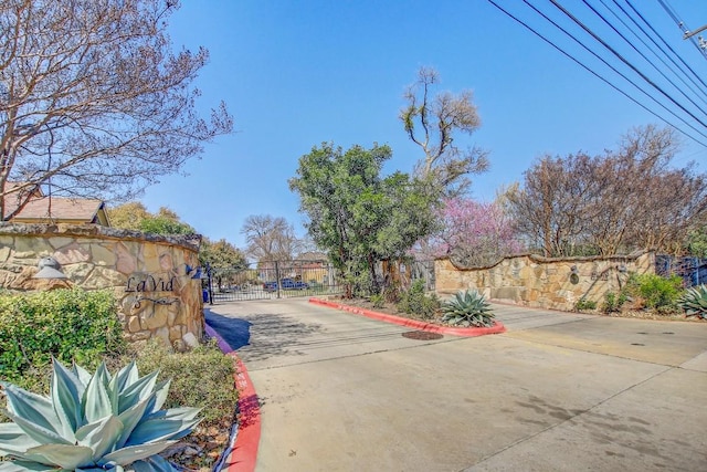 view of street with a gate, curbs, and a gated entry