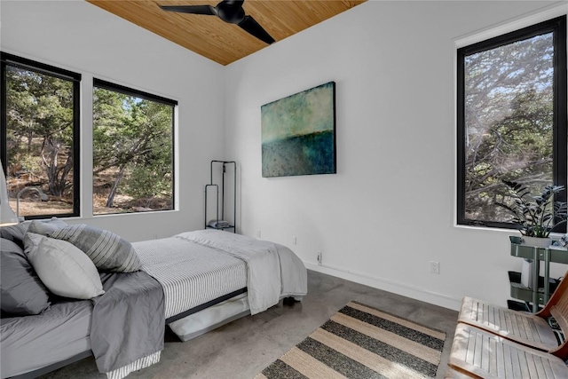 bedroom with finished concrete floors, wood ceiling, and baseboards