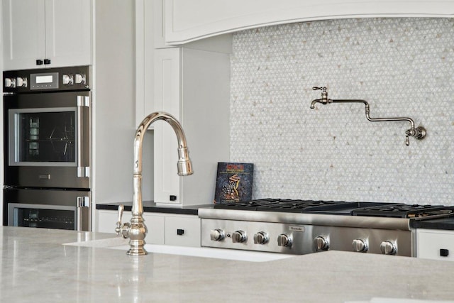 details featuring decorative backsplash, appliances with stainless steel finishes, and white cabinetry