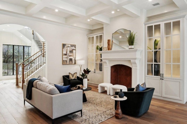 living area with visible vents, beamed ceiling, a fireplace, and coffered ceiling