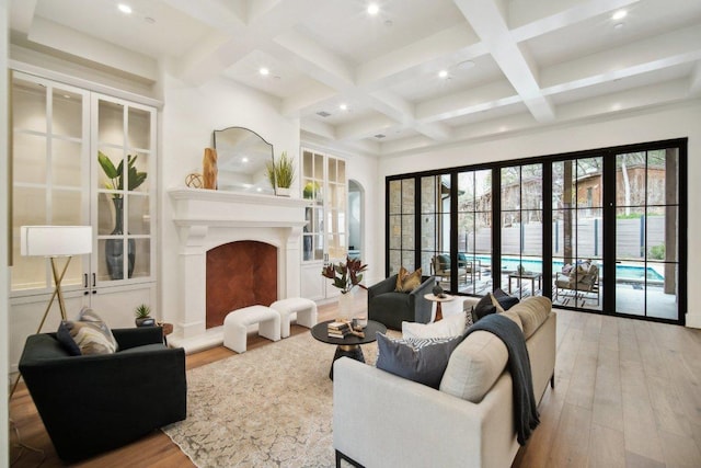 living area featuring beamed ceiling, coffered ceiling, and a fireplace with raised hearth