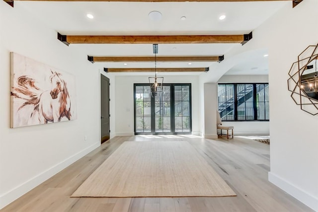 interior space featuring beam ceiling, baseboards, and light wood-style floors