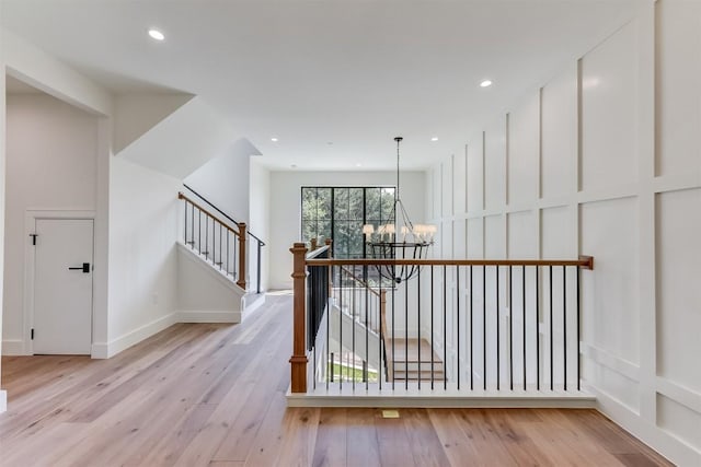 hall featuring an inviting chandelier, stairway, recessed lighting, and light wood-style floors