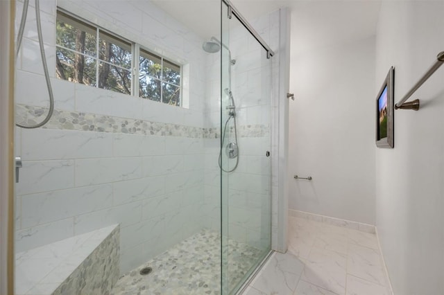 full bathroom with marble finish floor, a shower stall, and baseboards