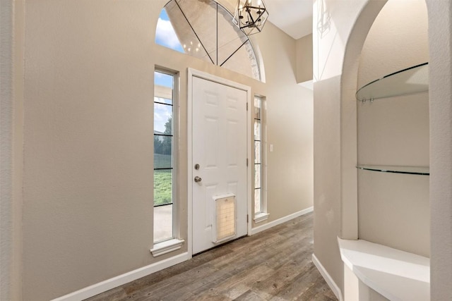 entryway featuring wood finished floors, baseboards, and a chandelier