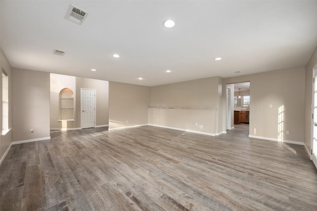 spare room featuring visible vents, wood finished floors, recessed lighting, arched walkways, and baseboards