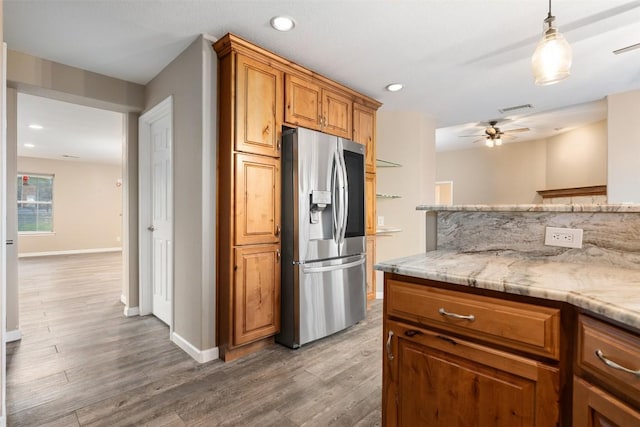 kitchen featuring visible vents, stainless steel fridge with ice dispenser, light wood-type flooring, light stone counters, and brown cabinetry