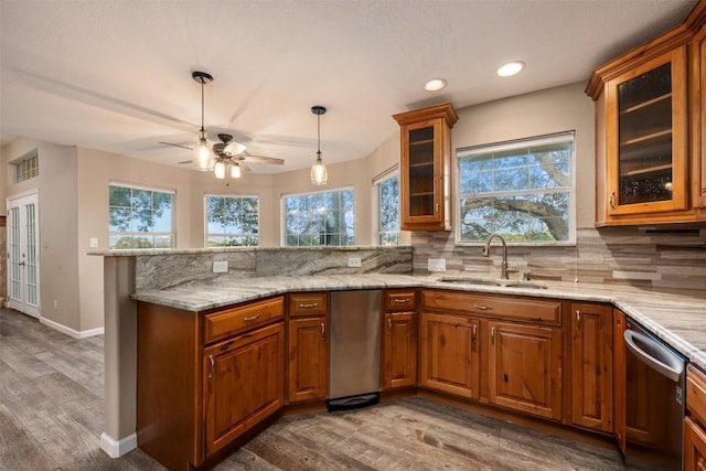 kitchen with a sink, dishwasher, a peninsula, and brown cabinetry