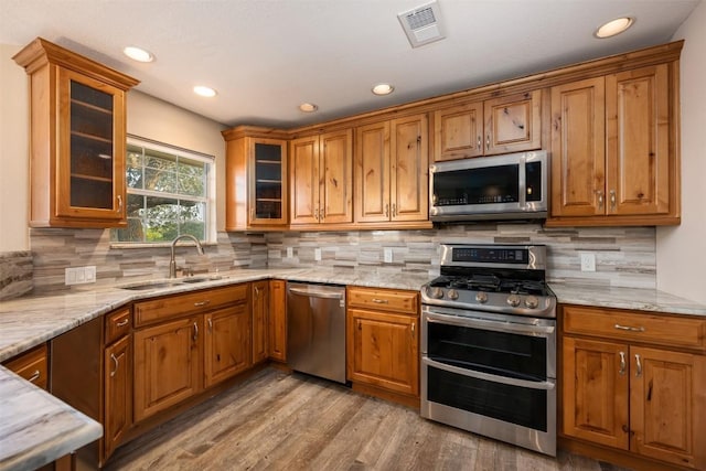 kitchen with a sink, stainless steel appliances, visible vents, and brown cabinetry