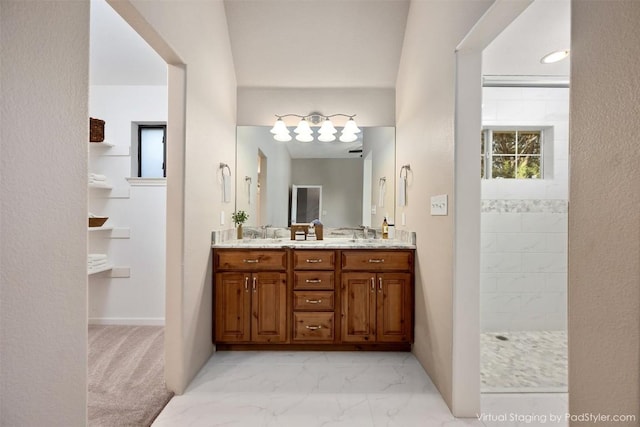 bathroom featuring a sink, marble finish floor, double vanity, and a walk in shower