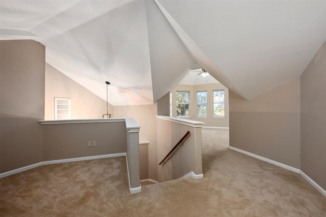 interior space featuring baseboards, light carpet, and vaulted ceiling