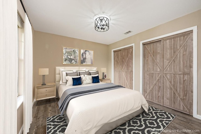 bedroom with visible vents, baseboards, multiple closets, and wood finished floors