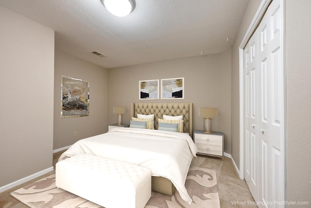 bedroom with visible vents, a textured ceiling, a closet, baseboards, and light colored carpet