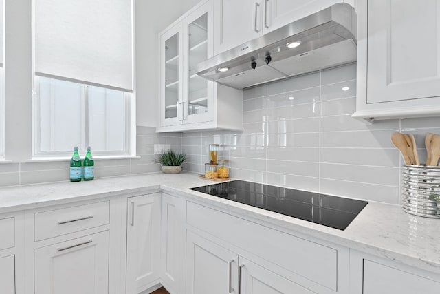 kitchen with extractor fan, black electric stovetop, tasteful backsplash, and white cabinets