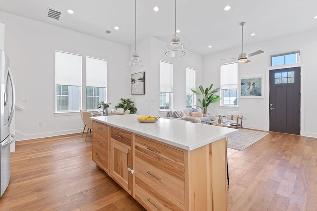 kitchen with visible vents, light brown cabinets, a center island, recessed lighting, and light wood-style floors