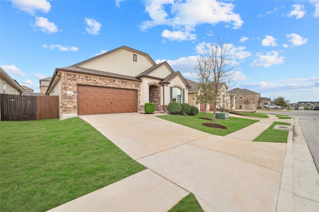 french country home featuring a garage, concrete driveway, fence, and a front yard