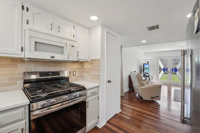 kitchen featuring white microwave, visible vents, stainless steel gas range, open floor plan, and backsplash