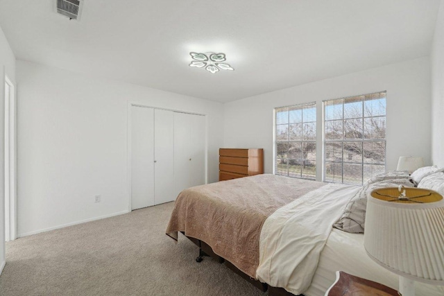 carpeted bedroom featuring visible vents, baseboards, and a closet