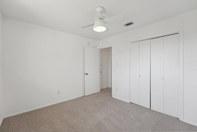 unfurnished bedroom featuring visible vents, light carpet, a closet, baseboards, and ceiling fan