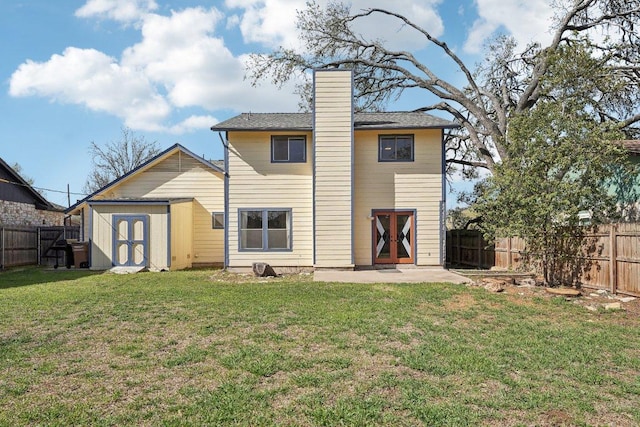 rear view of property featuring an outbuilding, a yard, a fenced backyard, a chimney, and a storage shed