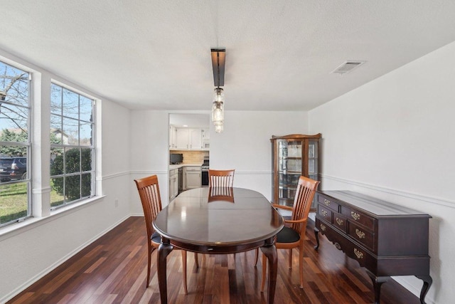 dining space featuring visible vents, baseboards, dark wood-type flooring, and a textured ceiling