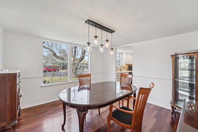 dining space with dark wood-style floors, baseboards, and a textured ceiling