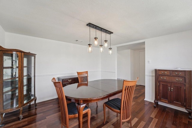 dining room with baseboards, dark wood-style floors, visible vents, and a textured ceiling