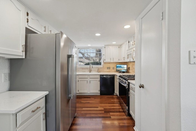 kitchen with backsplash, dark wood-type flooring, stainless steel appliances, white cabinetry, and a sink