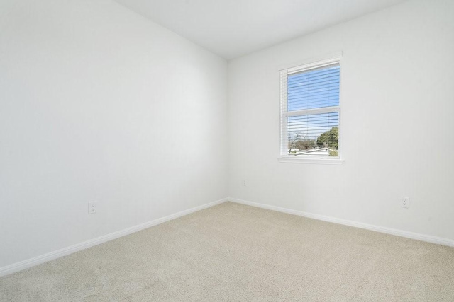 spare room featuring baseboards and light carpet