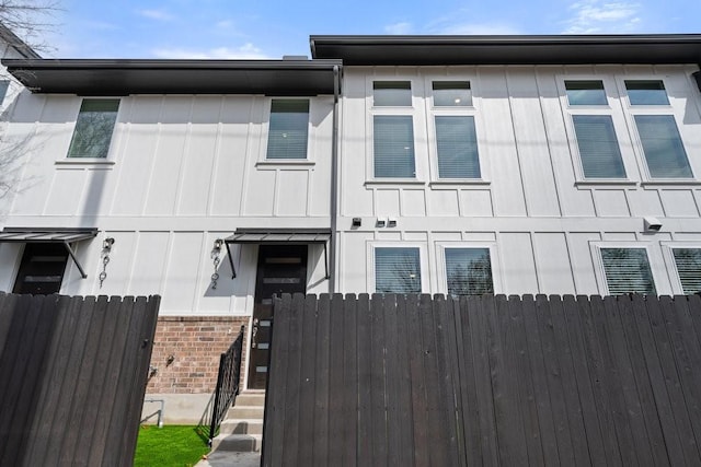 exterior space with brick siding, board and batten siding, and fence