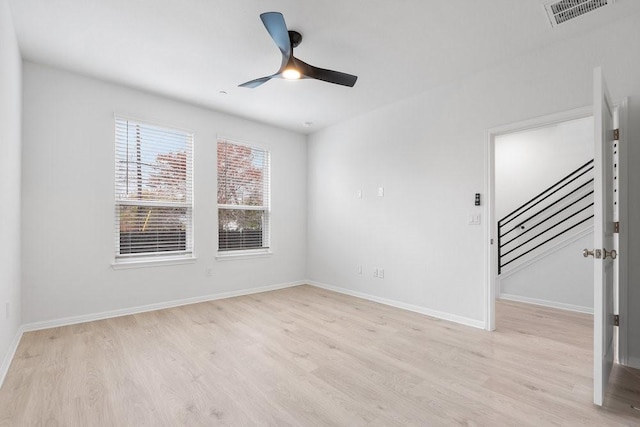 empty room with visible vents, baseboards, ceiling fan, stairs, and light wood-style flooring