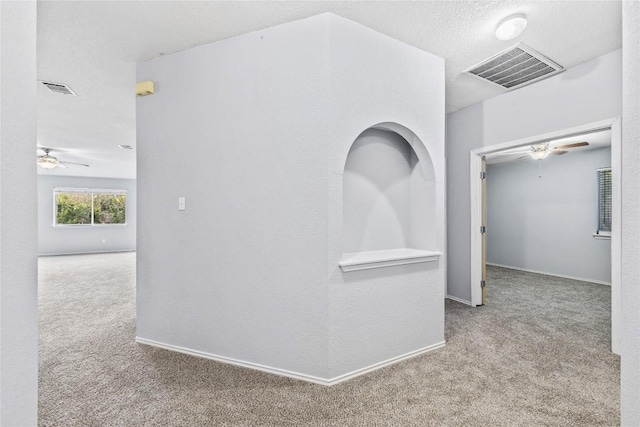 corridor with baseboards, carpet, visible vents, and a textured ceiling